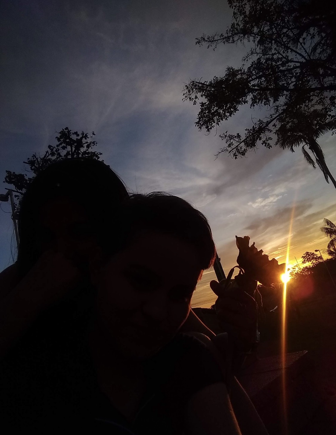 Cams e Heloíze em silhueta diante de um pôr do sol amazônico